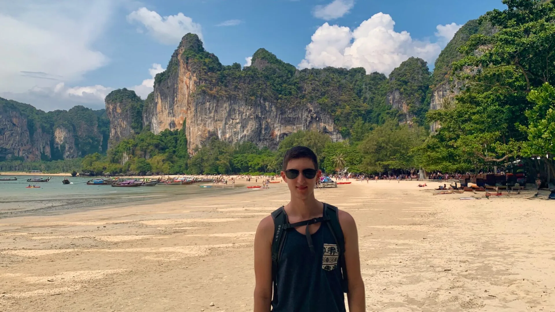 man standing on Railay Beach in thailand with limestone cliffs behind
