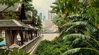 views of Bangkok city skyline with lush jungle and traditional houses