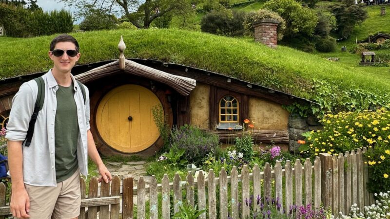 travel blogger next to hobbit hole at Hobbiton in Rotorua New Zealand
