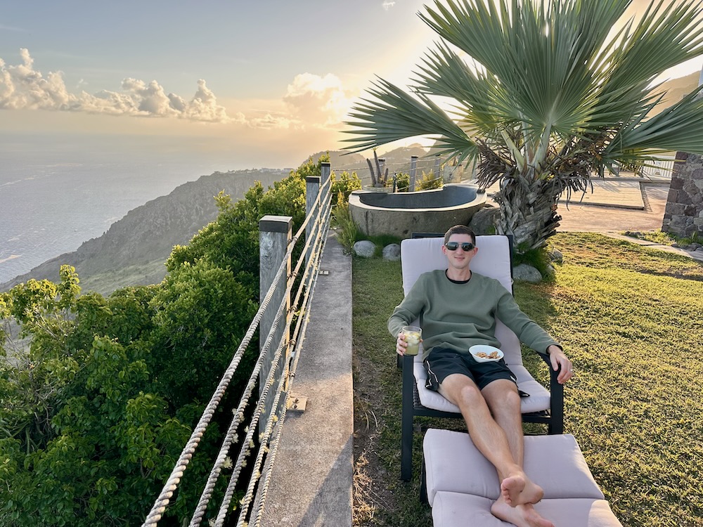 travel blogger lounging at villa in Caribbean at sunset views of cliffs and sea