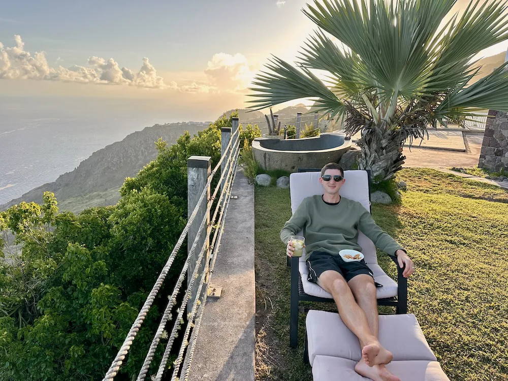 travel blogger lounging at villa in Caribbean at sunset views of cliffs and sea