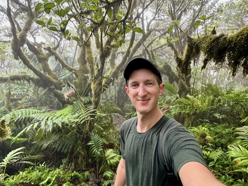 a man taking a selfie in a forest giving travel tips for visiting Saba
