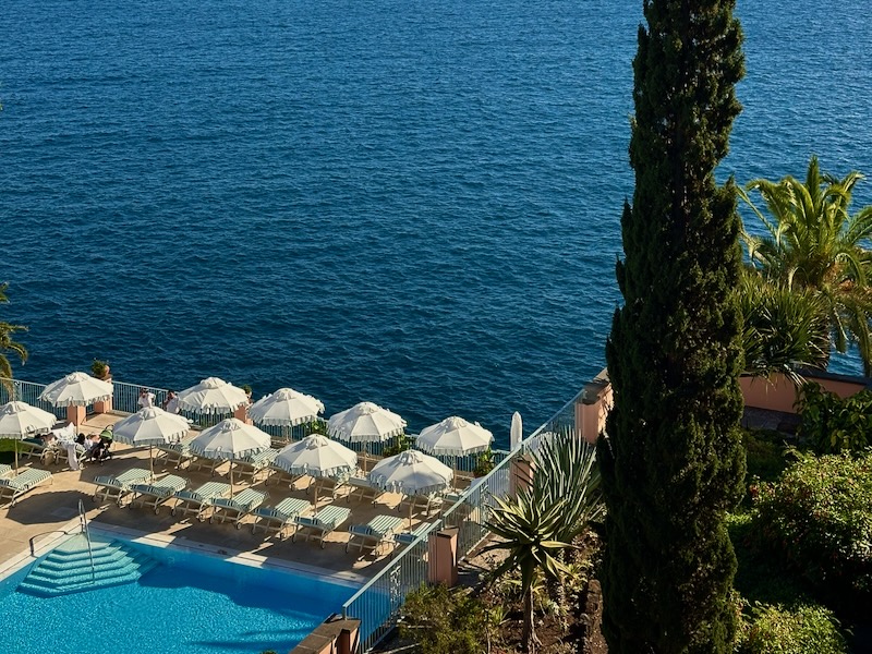 luxury pool with umbrellas overlooking the ocean at Reid's Palace Madeira